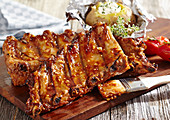 Grilled spare ribs with a baked potato on a wooden board
