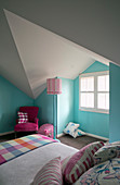 Bed and hot-pink chair in room with pale blue walls