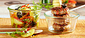 Grilled meat patties with a Greek potato salad and olives in a preserving jar