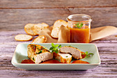 Grilled chicken breast with a spicy apricot sauce in a preserving jar served with baguette