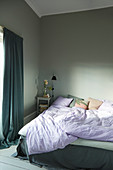 Rumpled bed in grey bedroom