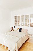 Blanket with tassels on bed below internal bedroom window