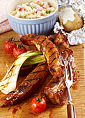 Grilled spare ribs with grilled vegetables, a baked potato and a pasta salad