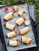 Sausages wrapped in pastry on a baking tray