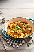 Spring casserole with chicken tights, new potatoes, baby carrots, young cabbage, broad beans and sage