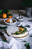 Tasty appetizing decorated with mandarin green and nuts tangerine cake and whole citruses knife bowl with spoon on table