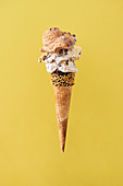 Toffee and snickers ice cream scoops oh a haselnut cone.