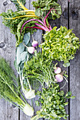 Various garden vegetables, lettuce and herbs on a wooden surface