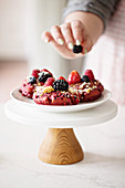 Berry shortcake donuts with a chefs hand putting fresh berries on top