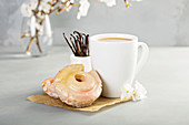 Vanilla old fashioned fried donuts with pink glitter glaze and a cup of coffee
