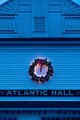 Christmas wreath with lights on outside wall of building at twilight
