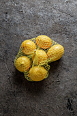 Ein Netz Zitronen auf Steinuntergrund