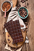 Schokoladentafeln, Kakaopulver und Kakaobohnen auf Holzbrett