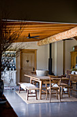 Wooden table, benches and chairs in rustic dining room with wooden ceiling beams