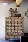 Lantern and horse sculpture on top of vintage apothecary cabinet