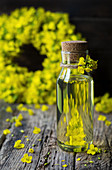 Rapeseed oil in a small bottle and rapeseed flowers