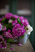 Pink and white roses in metal vase on wooden table