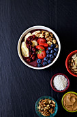 Pitaya bowl with bananas, blueberries almonds, strawberries, coconuts flakes and cranberries, peanut butter