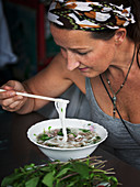 Frau isst eine thailändische Nudelsuppe