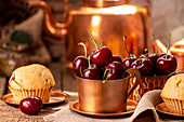 Sweet cherries in cooper cups and muffins against old vintage cooper dish