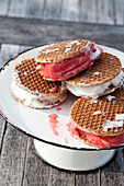 A cake stand filled with raspberry and vanilla ice cream sandwiches, beginning to melt