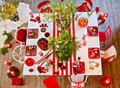 Gedeckter Weihnachtstisch in Rot-Weiß mit Christbäumchen