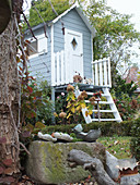 Holzhäuschen mit Treppe in herbstlichem Garten