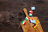 Various mini paper flags on a wooden board on a wooden surface