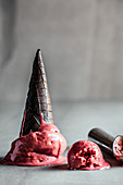 Schmelzendes Erdbeer-Lakritz-Eis mit schwarzer Eistüte