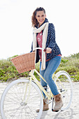 Junge Frau in Jeans, Sweatshirt, Kapuzenjacke und Pelzstiefeln auf Fahrrad