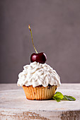 Cupcake mit Sahnehäubchen und Kirsche verziert