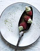 Raspberries, filled with vegan matcha tea cream, on a spoon