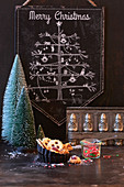 Weihnachtsbaum-Tafel, im Vordergrund Tannenbäumchen, Plätzchen und Vintage Backform