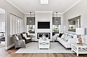 Couch, coffee table, fireplace and designer armchair in pale, elegant living room