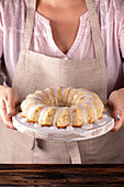 Iced sugar cake on tray in woman hands