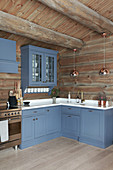 Blue cupboards in large country-house kitchen of log cabin