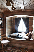 Cosy cubby bed with window in rustic log cabin