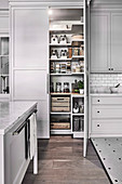 Open storage cupboard in a country house kitchen with grey fronts