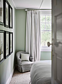 Gray upholstered armchair in corner of bedroom near window