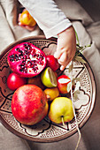Close-up of child taking fruit from bowl