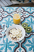 Müsli mit Leinsamen und Bananen, Orangensaft und Kiwi zum Frühstück