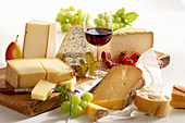 A still life of french cheeses with red wine and grapes