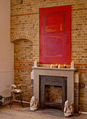 Red artwork above mantelpiece on brick wall