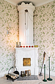 Antique, white stove in corner of living room with floral wallpaper