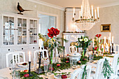 Long, festively set dining table below chandelier in dining room of manor house