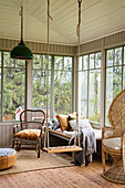 Swing, couch with cushions, wicker armchair and peacock chair in conservatory