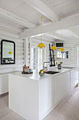 White island counter in kitchen of in white-painted log cabin