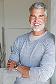 A grey-haired man wearing a light-grey jumper over an under shirt