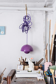 Purple pendant lamp above craft utensils on workbench