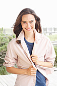 A young brunette woman wearing a blue t-shirt with a pale pink shirt blouse